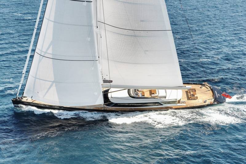 A sleek white sailboat glides through the deep blue ocean waves, its sails catching the wind.