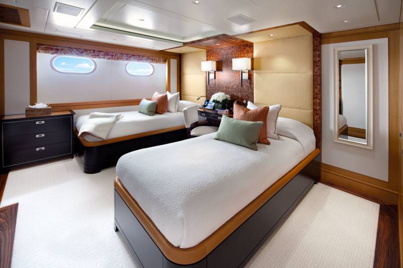 Luxurious twin beds with plush white bedding and accent pillows create a serene retreat in this elegant stateroom.