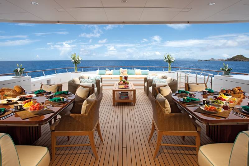A beautifully set table awaits a delightful breakfast on the deck of a luxury yacht overlooking the ocean.