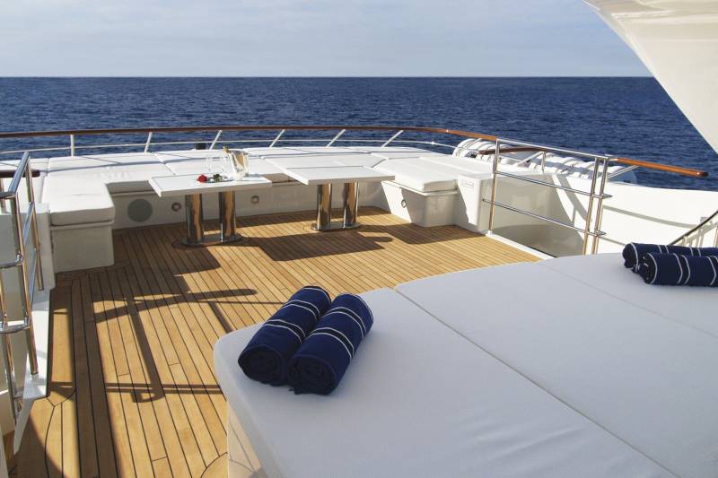 A romantic setting awaits on the deck of this luxurious yacht with champagne and a rose by the tranquil blue sea.