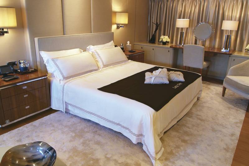 Luxurious robes await on a neatly made bed in this opulent stateroom.