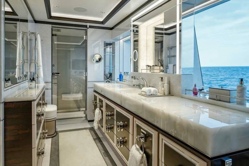 Luxurious yacht bathroom features a marble vanity, glass shower, and ocean views.