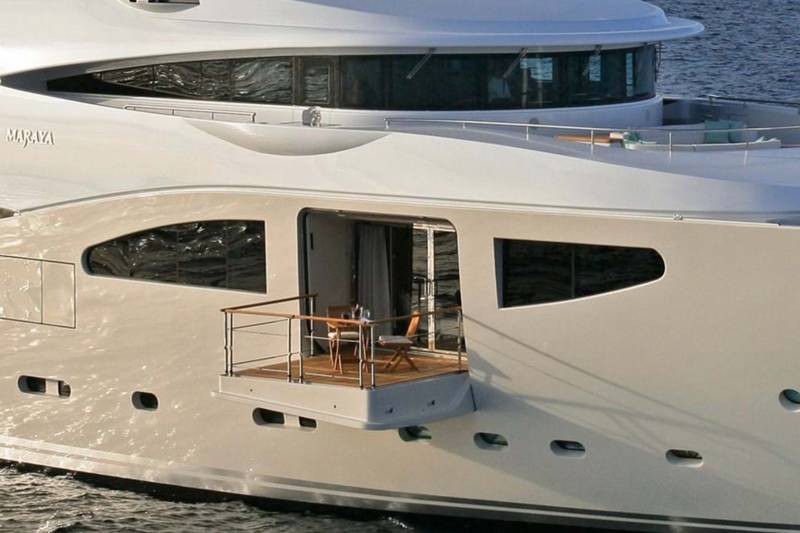 A luxurious yacht named MARAYA glides through the water, featuring a private balcony with seating.