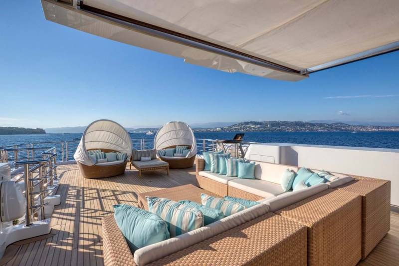Luxurious outdoor seating on a yacht deck offers a serene spot to enjoy the sparkling blue sea and distant coastline.