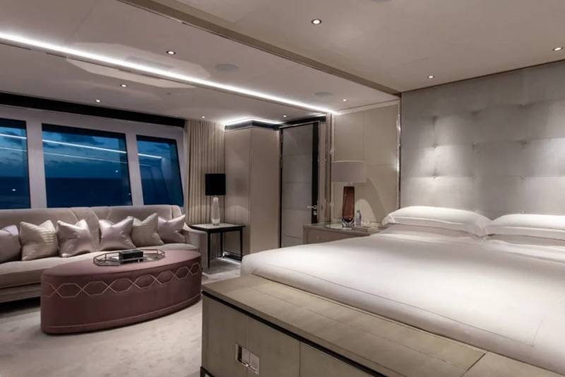 Luxurious yacht accommodations offer a serene bedroom with ocean views and plush seating.