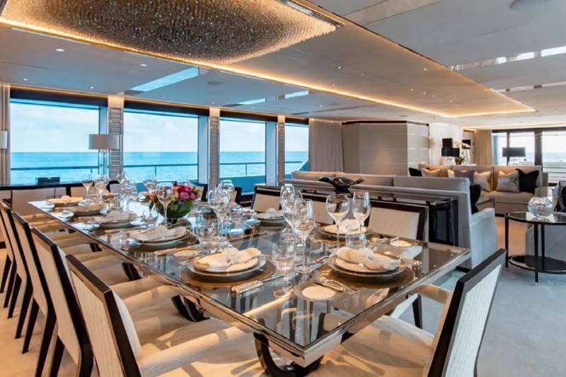 A grand dining table is set for a feast aboard a luxurious yacht, overlooking the serene ocean.