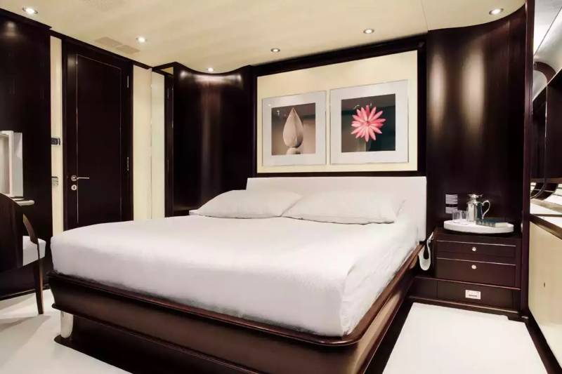 Luxurious dark wood paneling and crisp white linens create a serene and elegant master suite on this yacht.