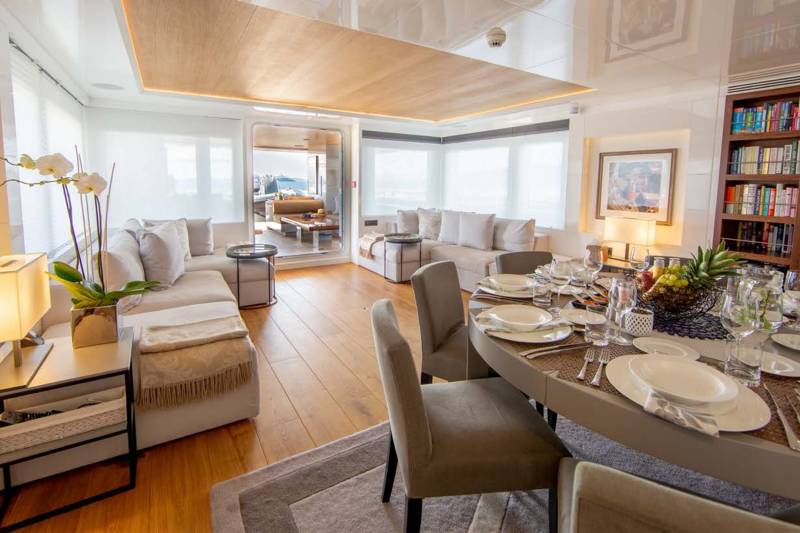 A beautifully set dining table awaits guests in this luxurious yacht interior, bathed in soft, ambient light.