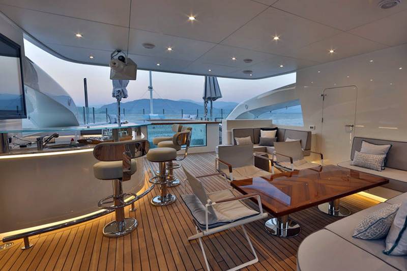 Relax in style on this luxurious yacht's deck, complete with a sleek bar, comfortable seating, and stunning ocean views.