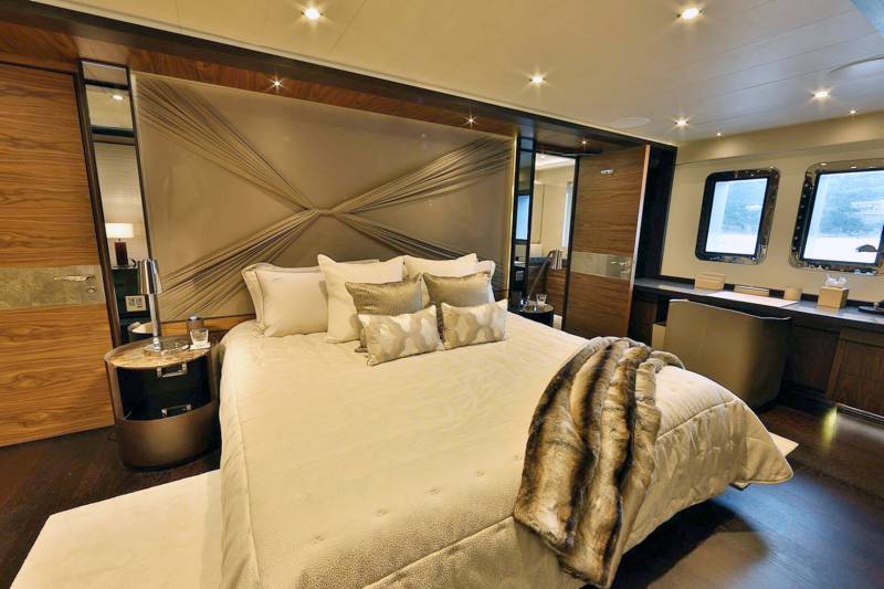 Luxurious yacht accommodations feature a plush bed, elegant headboard, and a desk with a view of the water.