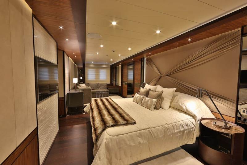 Luxurious yacht accommodations feature a plush bed, rich wood accents, and a sleek entertainment system.