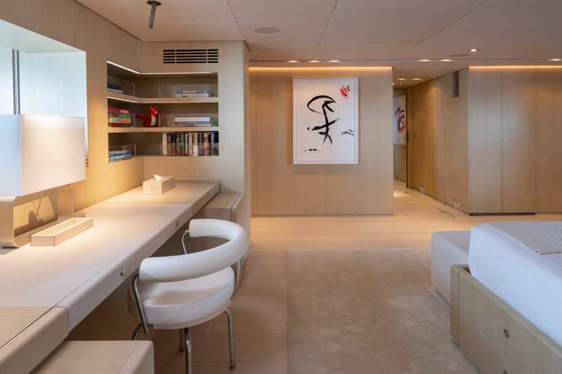 A minimalist bedroom features a sleek desk with a white chair, built-in shelving, and a contemporary artwork adorning the wood-paneled wall.