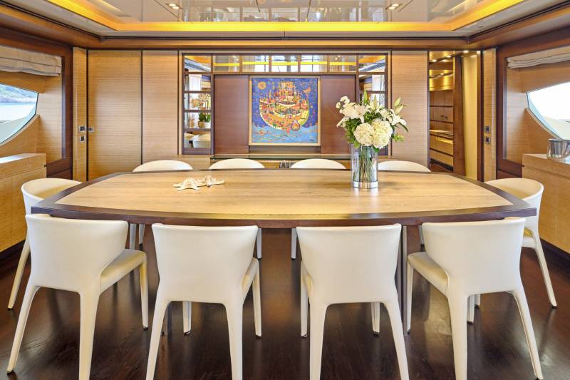 Dine in elegant comfort aboard this luxurious yacht, surrounded by warm wood paneling and a vibrant piece of art.