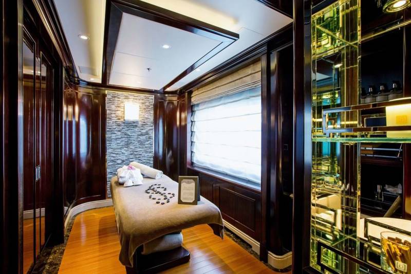 Indulge in ultimate relaxation within this opulent spa room, featuring a plush massage table and elegant mirrored accents.