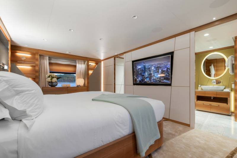 Luxurious bedroom and ensuite bathroom featuring a city skyline on the television and a view of the water.
