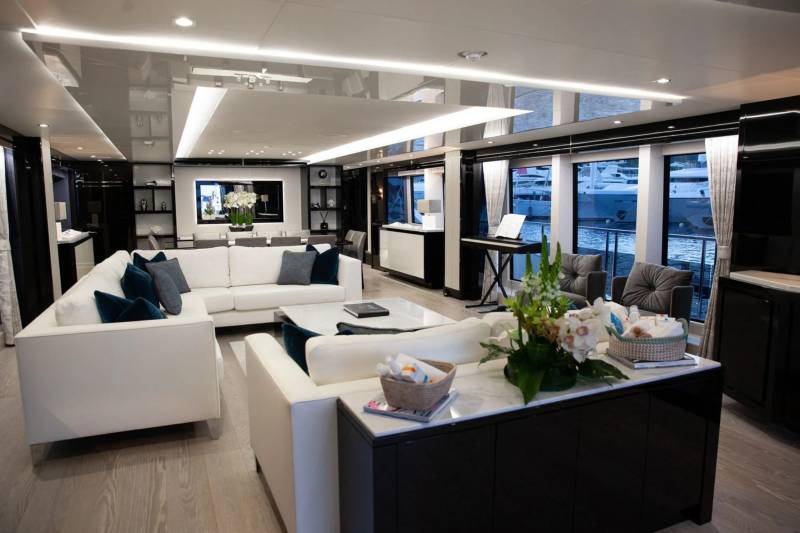 Luxurious yacht interiors offer stunning views of docked vessels through expansive windows.