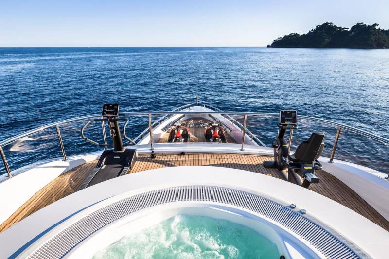 Enjoy a workout with a view on this luxurious yacht's sundeck, complete with a jacuzzi and state-of-the-art gym equipment.