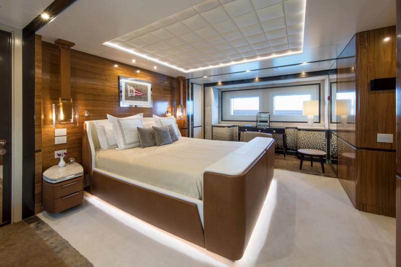 Luxurious yacht accommodations feature a plush king-size bed, elegant wood paneling, and ambient lighting for a serene retreat at sea.