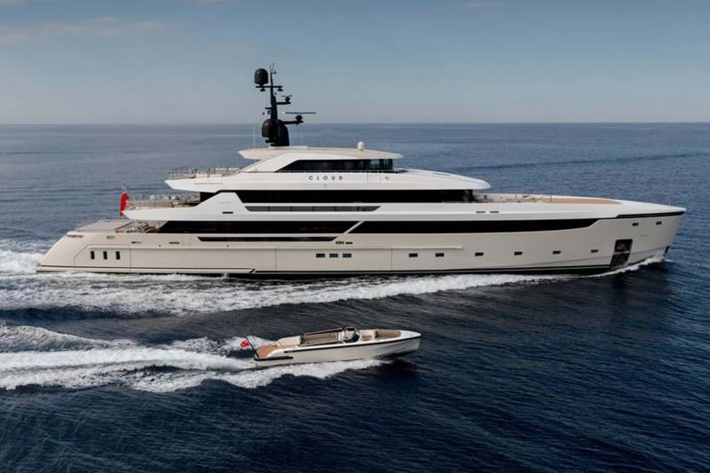 A sleek superyacht named "Cloud" cruises through the deep blue sea, accompanied by a smaller tender boat.