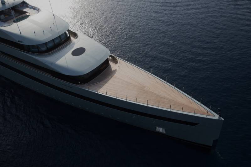 A large, sleek yacht with a wooden deck and a dark, expansive body of water in the background.