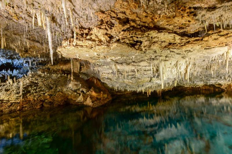 Stalactites hang like icicles above the crystal-clear turquoise water of this breathtaking cave.