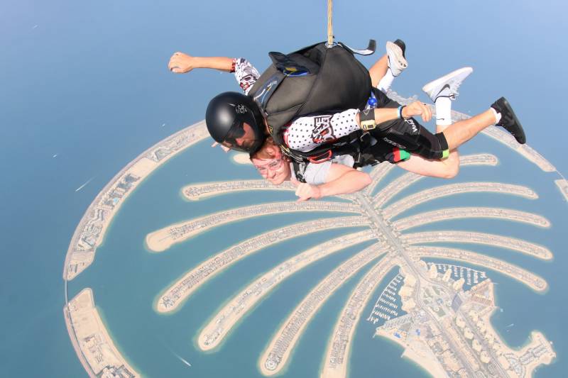 Two skydivers enjoy a breathtaking aerial view of Dubai's iconic Palm Jumeirah during their thrilling descent.