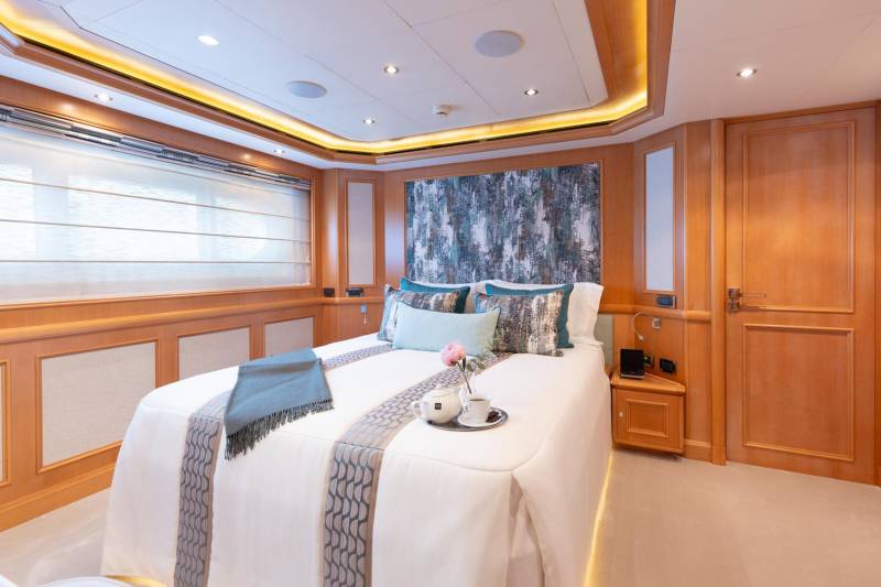 Luxurious yacht cabin features a plush bed adorned with decorative pillows and a serene blue throw.