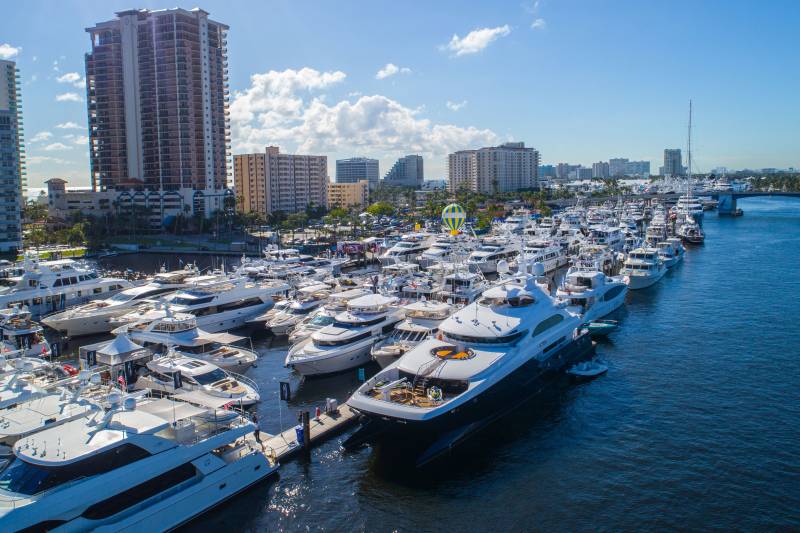 Dozens of luxurious yachts are docked in a vibrant harbor under a clear blue sky.