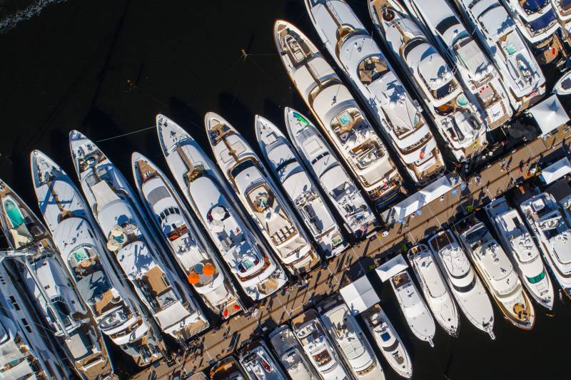 Dozens of luxury yachts are docked in a marina, showcasing their sleek designs and opulent amenities.
