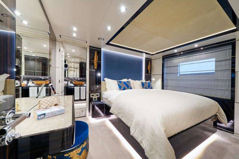 Luxurious yacht bedroom features a plush bed, mirrored vanity, and ambient lighting for ultimate comfort.