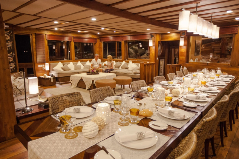 A long, elegantly set dining table awaits guests in this warmly lit, wood-paneled room.