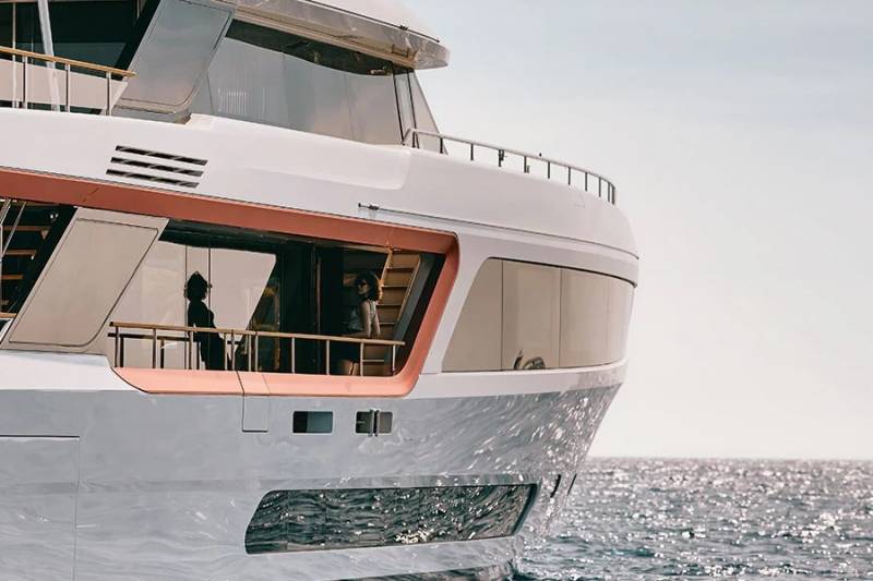 A luxurious yacht glides across the sparkling sea under a clear sky.