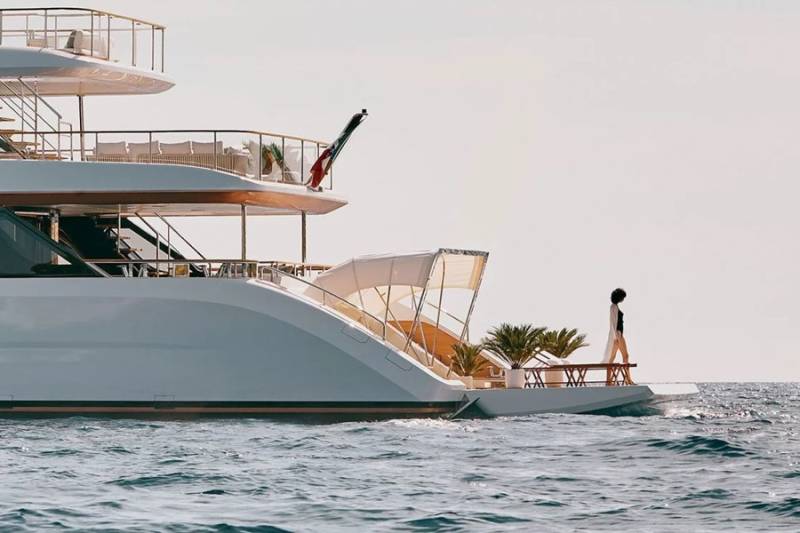 A lone figure stands on the deck of a luxurious yacht, enjoying the serene ocean view.