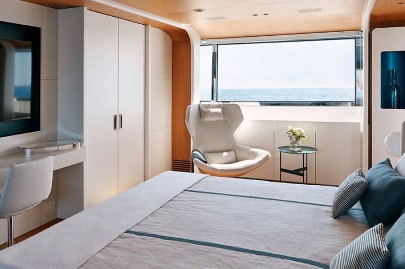 A luxurious bedroom offers stunning ocean views from a large window, complemented by modern furnishings and a comfortable bed.