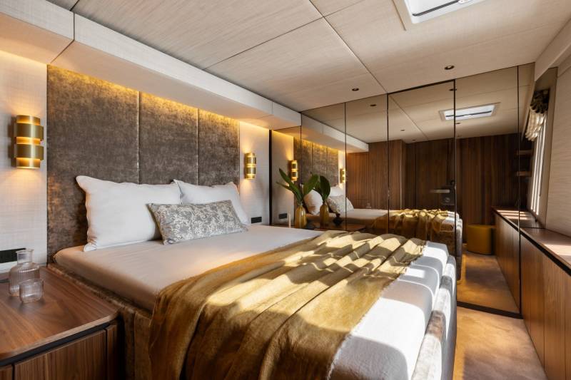 Luxurious yacht cabin features a plush bed, ambient lighting, and mirrored walls for an expansive feel.