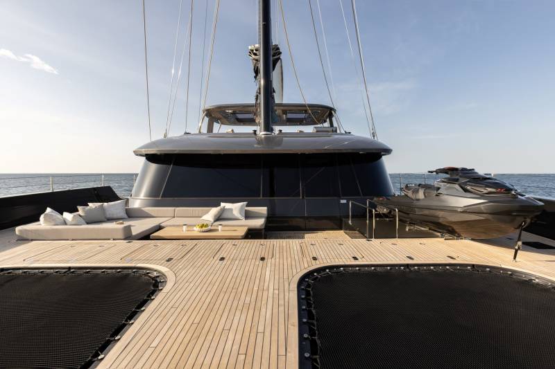 A modern catamaran offers luxurious deck space with a plush lounge area, a jet ski, and a trampoline for ultimate seaside enjoyment.