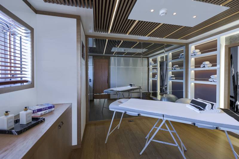 This luxurious spa room features massage tables, neatly folded towels, and a calming ambiance with wooden accents and soft lighting.