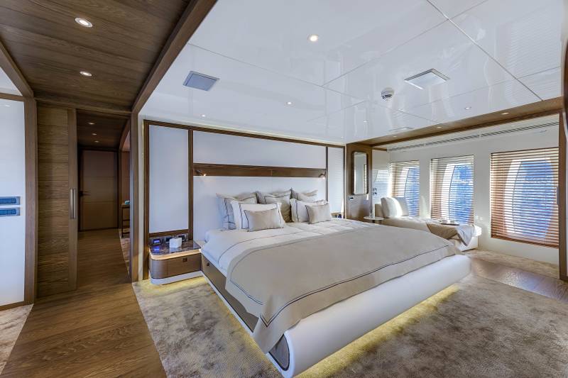 Luxurious yacht master suite features a king-size bed, elegant wood accents, and stunning ocean views.