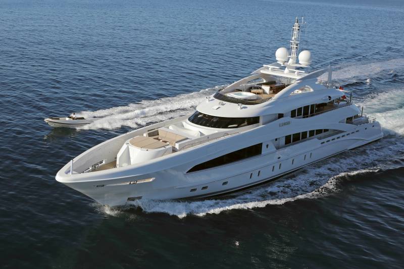 A sleek white yacht cruises through the deep blue ocean, leaving a foamy wake behind it.
