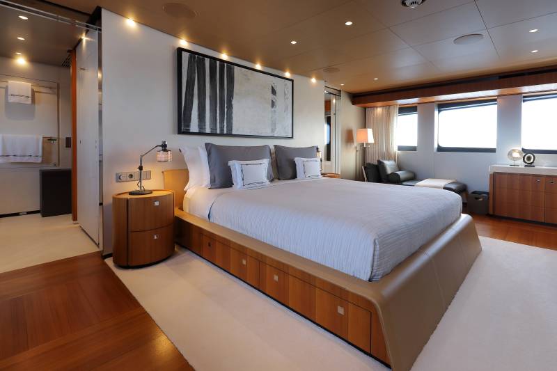 Luxurious yacht accommodations feature a spacious master suite with plush bedding, elegant artwork, and ample storage.