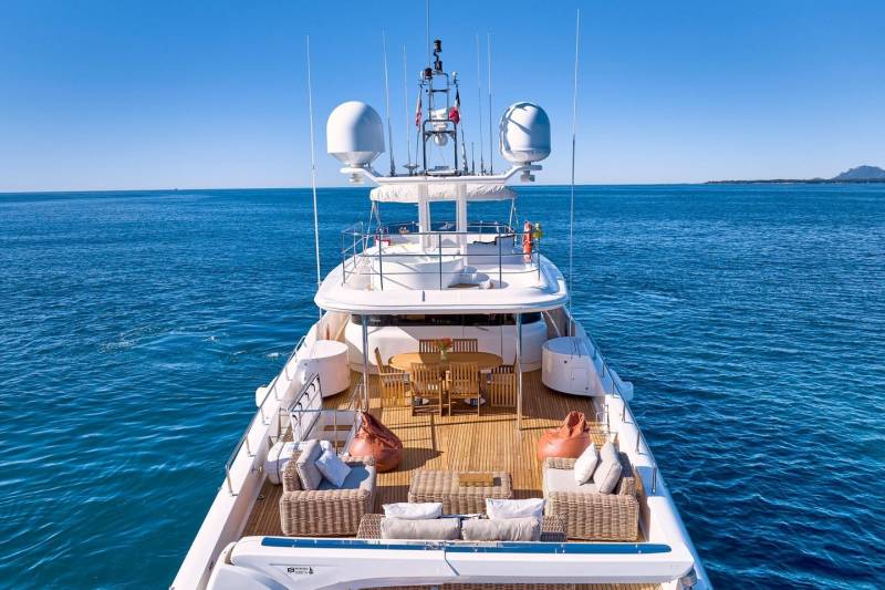 A luxurious yacht glides through the calm blue ocean under a clear sky.