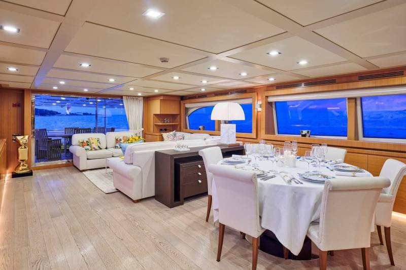 A luxurious yacht interior features a formal dining setting and a comfortable lounge area with ocean views.