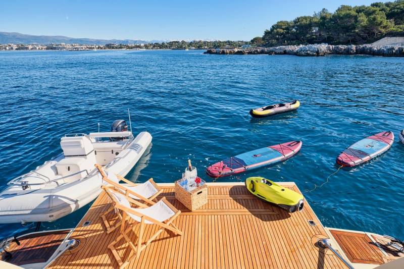 A luxurious yacht deck offers a perfect spot to relax with a bottle of champagne and enjoy the azure waters, paddleboards, and a tender.