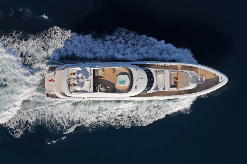 A luxurious yacht glides through the deep blue ocean, leaving a trail of white foam in its wake.