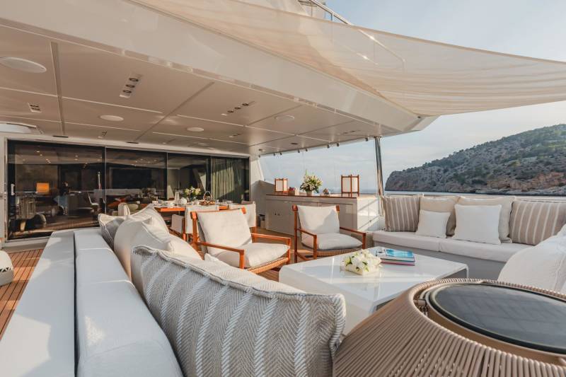 Relax on the luxurious deck of a yacht, surrounded by plush seating and breathtaking coastal views.