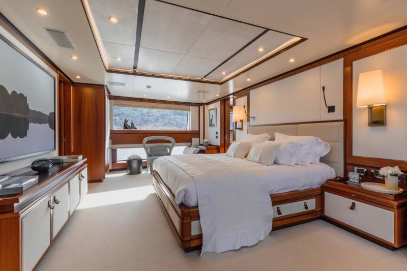 Luxurious yacht stateroom offers a serene retreat with plush bedding, elegant wood finishes, and scenic ocean views.