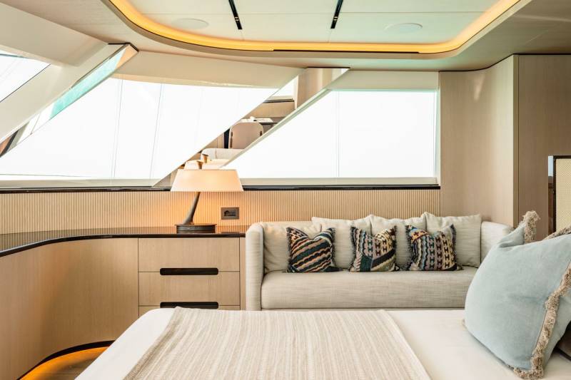Luxurious yacht interiors feature a serene bedroom with a plush sofa, decorative pillows, and ambient lighting.