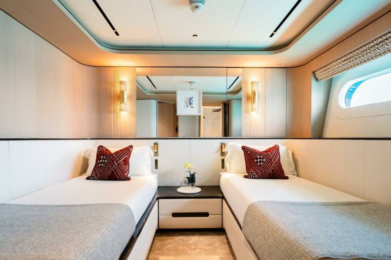 Twin beds with decorative pillows and soft grey throws are neatly made in this luxurious yacht cabin.