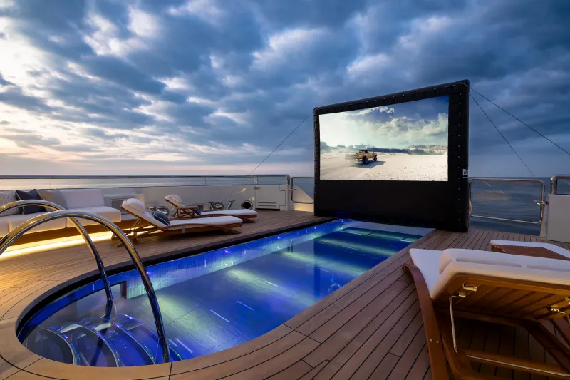 Enjoy an outdoor movie night with a refreshing dip in the pool on this luxurious yacht deck.