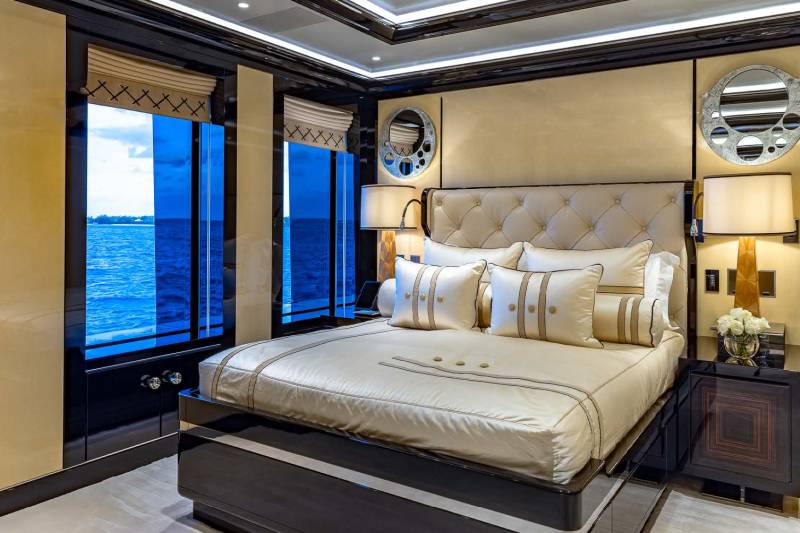 Luxurious yacht bedroom offers stunning ocean views through expansive blue-tinted windows.